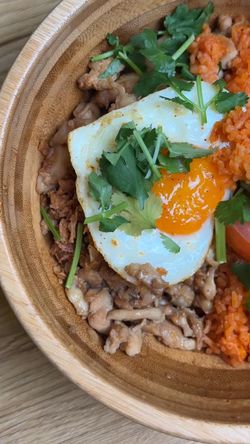 Bowl asiatique avec œuf au plat, viande hachée, riz assaisonné et coriandre fraîche dans un bol en bois.