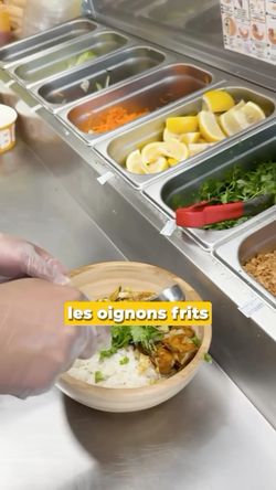 Préparation d'un plat avec du riz et des garnitures dans un restaurant asiatique.