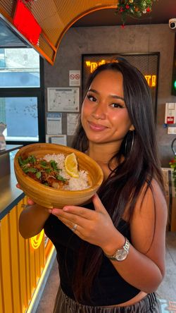 Plat asiatique avec riz, viande et citronniers présenté dans un bol en bois dans un restaurant asiatique.