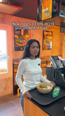Client dans le restaurant asiatique BOLKIRI Amiens avec un bol de nourriture sur un plateau près de la caisse.