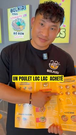 Un employé de BOLKIRI présentant le menu avec une recommandation pour le poulet loc lac.