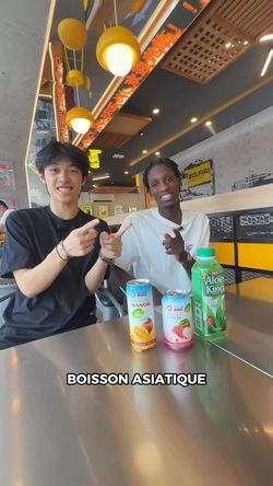 Deux personnes souriantes présentent des boissons asiatiques sur une table dans un restaurant asiatique.