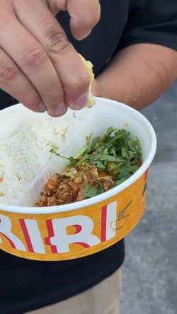 Un plat asiatique avec du riz, de la viande émincée, des herbes fraîches et du citron.