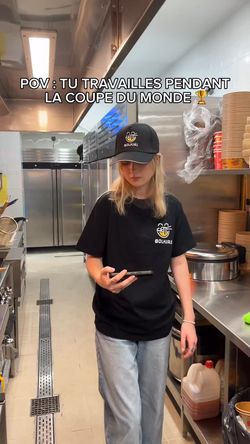 Employée portant un t-shirt et une casquette BOLKIRI dans une cuisine de restaurant asiatique sur Antony.