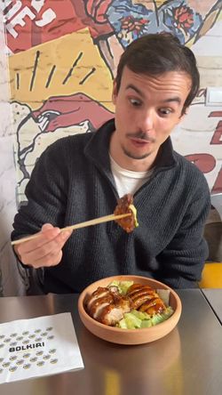 Plat asiatique dans un restaurant avec un client portant des baguettes à la main.