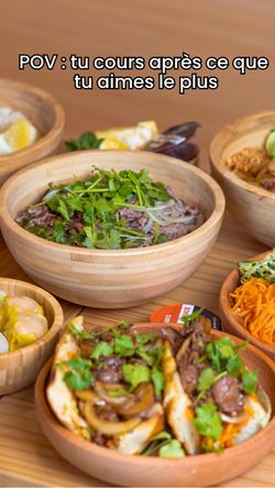 Plats variés asiatiques dans des bols en bois, avec des herbes fraîches et de la viande, restaurant asiatique.