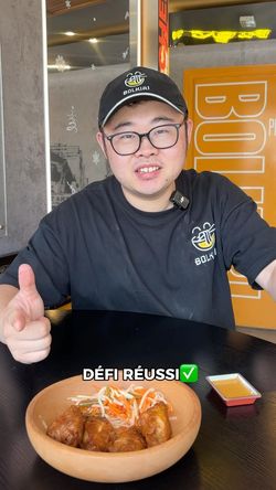 Homme portant casquette et t-shirt BOLKIRI dans un restaurant asiatique avec un bol de boulettes et sauces sur la table.