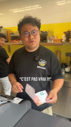 Serveur d'un restaurant asiatique tenant un billet de 70 euros, avec une expression étonnée .