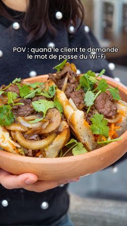 Plat asiatique dans un bol avec viande, champignons et coriandre, tenu par une personne en tenue de restaurant.