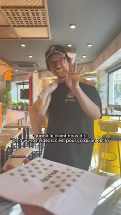 Serveur en uniforme dans un restaurant asiatique BOLKIRI avec intérieur moderne et chaises jaunes près des fenêtres.