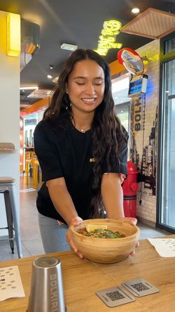 Serveuse souriante tenant un bol de plat asiatique dans le restaurant asiatique BOLKIRI Antony Street Food Viêt