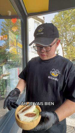 Employé du restaurant asiatique BOLKIRI tenant un bol en bois avec un plat vietnamien à l'intérieur.