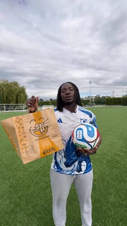 Personne sur un terrain de football tenant un sac du restaurant asiatique BOLKIRI Mantes-La-Jolie et un ballon de football.