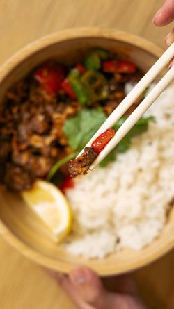 Savoureuse assiette de cuisine asiatique avec viande, légumes colorés et riz, agrémentée d'un quartier de citron.