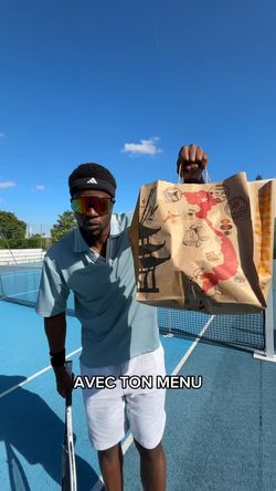 Homme tenant un sac en papier avec un dessin du Vietnam, sur un terrain de tennis, lié à un restaurant asiatique.