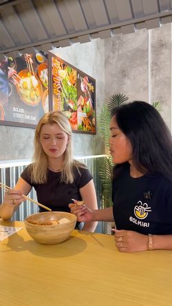 Deux femmes mangent dans un restaurant asiatique BOLKIRI Lens Street Food Viêt, décor moderne et affiches colorées.