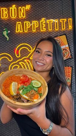 Jeune femme tenant un bol de nourriture vietnamienne avec poisson, riz et légumes au restaurant asiatique