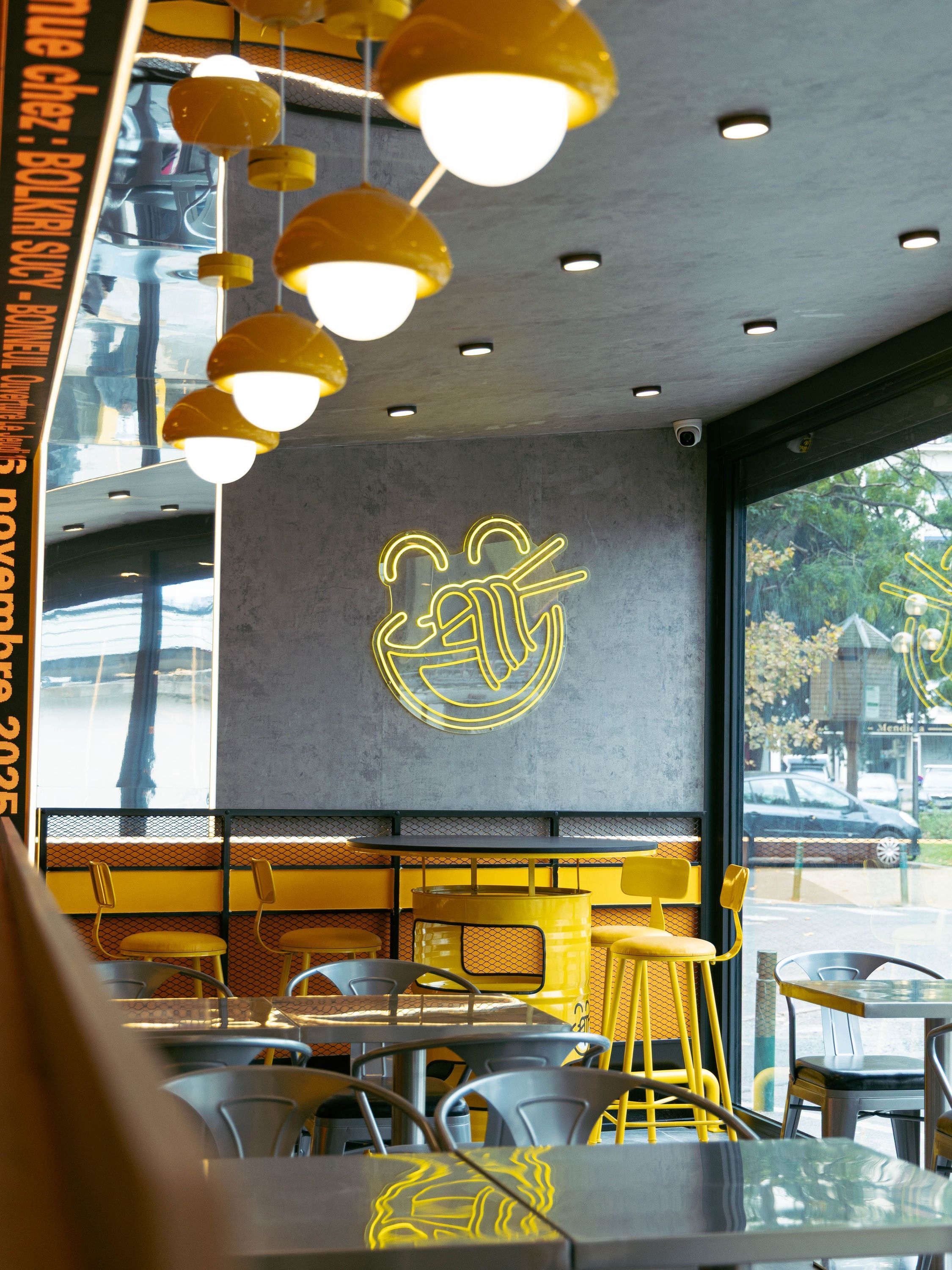 Intérieur du restaurant asiatique BOLKIRI avec sièges jaunes, tables en métal et décoration murale lumineuse.