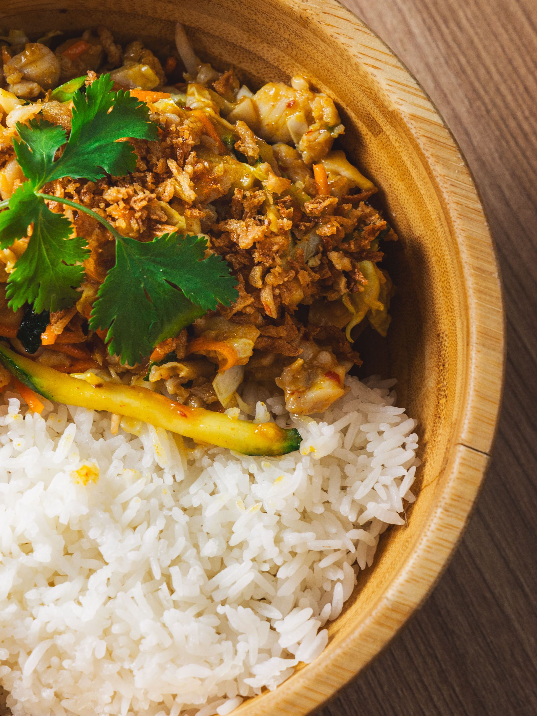 Bol de riz blanc accompagné de légumes sautés et de coriandre dans un restaurant asiatique.