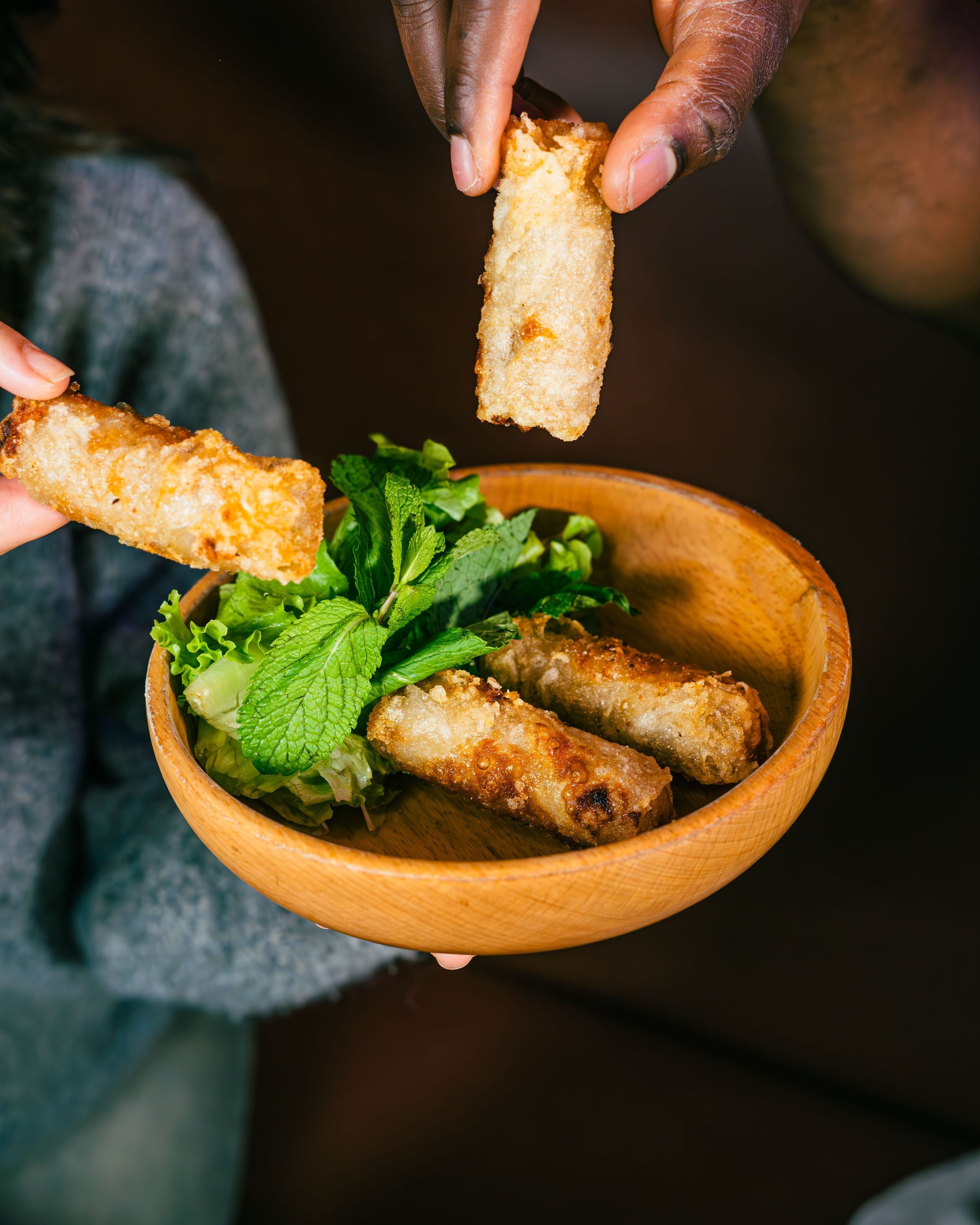 Rolls croustillants servis avec de la salade et des herbes fraîches dans un bol en bois.