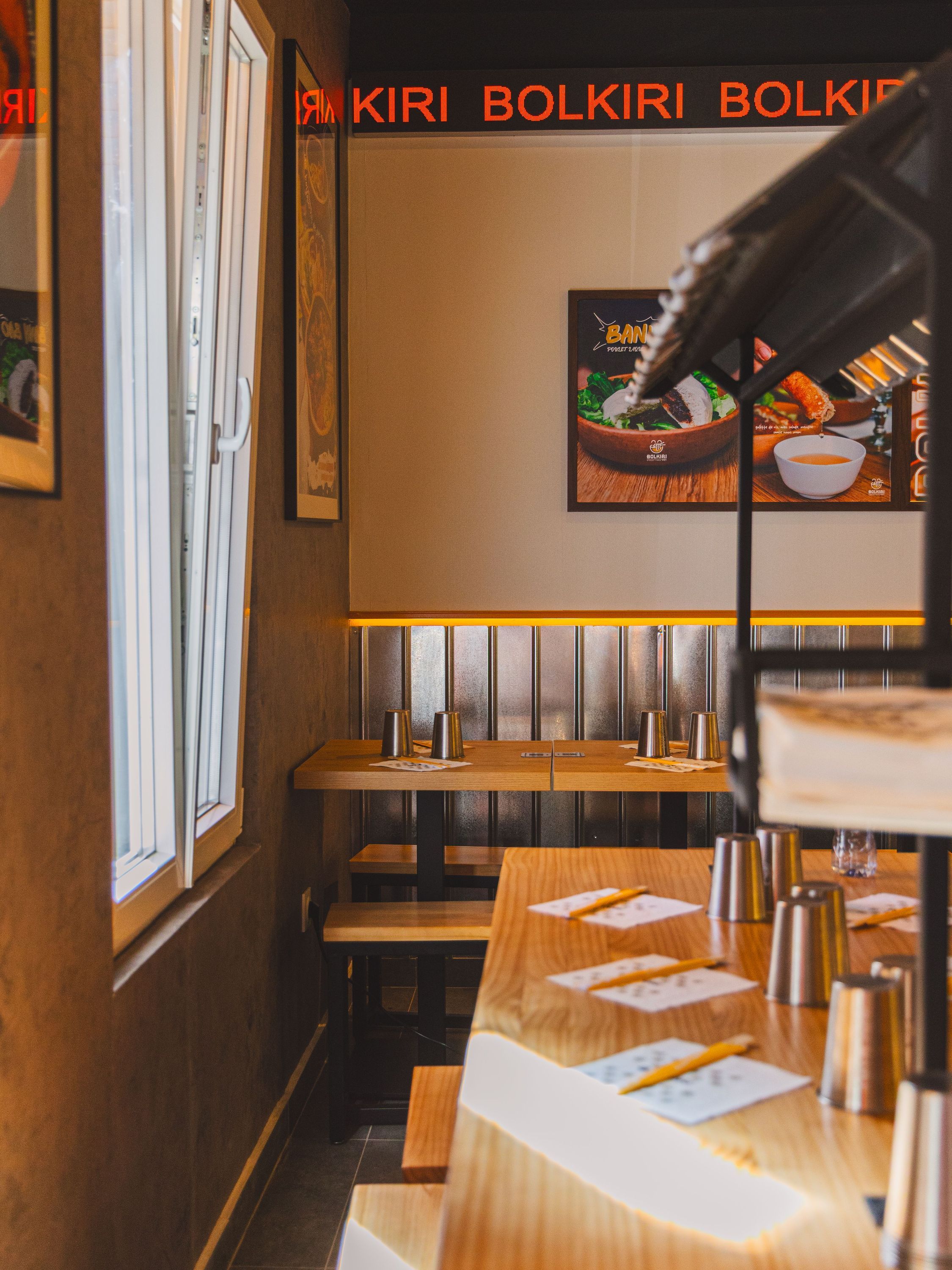Intérieur du restaurant asiatique BOLKIRI avec tables en bois, lampes suspendues et décoration moderne.