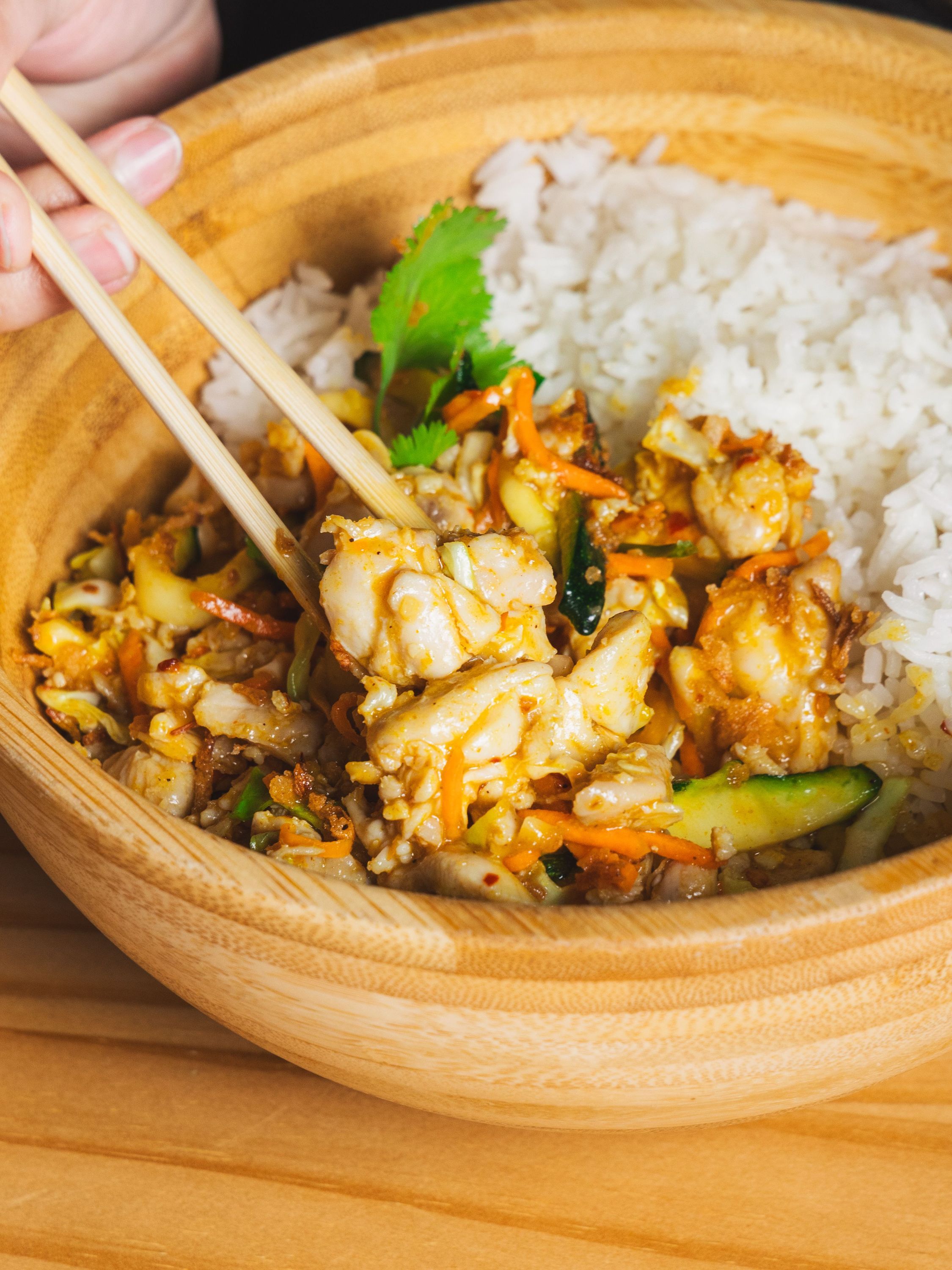 Plat asiatique avec poulet, riz blanc et légumes servi dans un bol en bois dans le restaurant asiatique BOLKIRI.