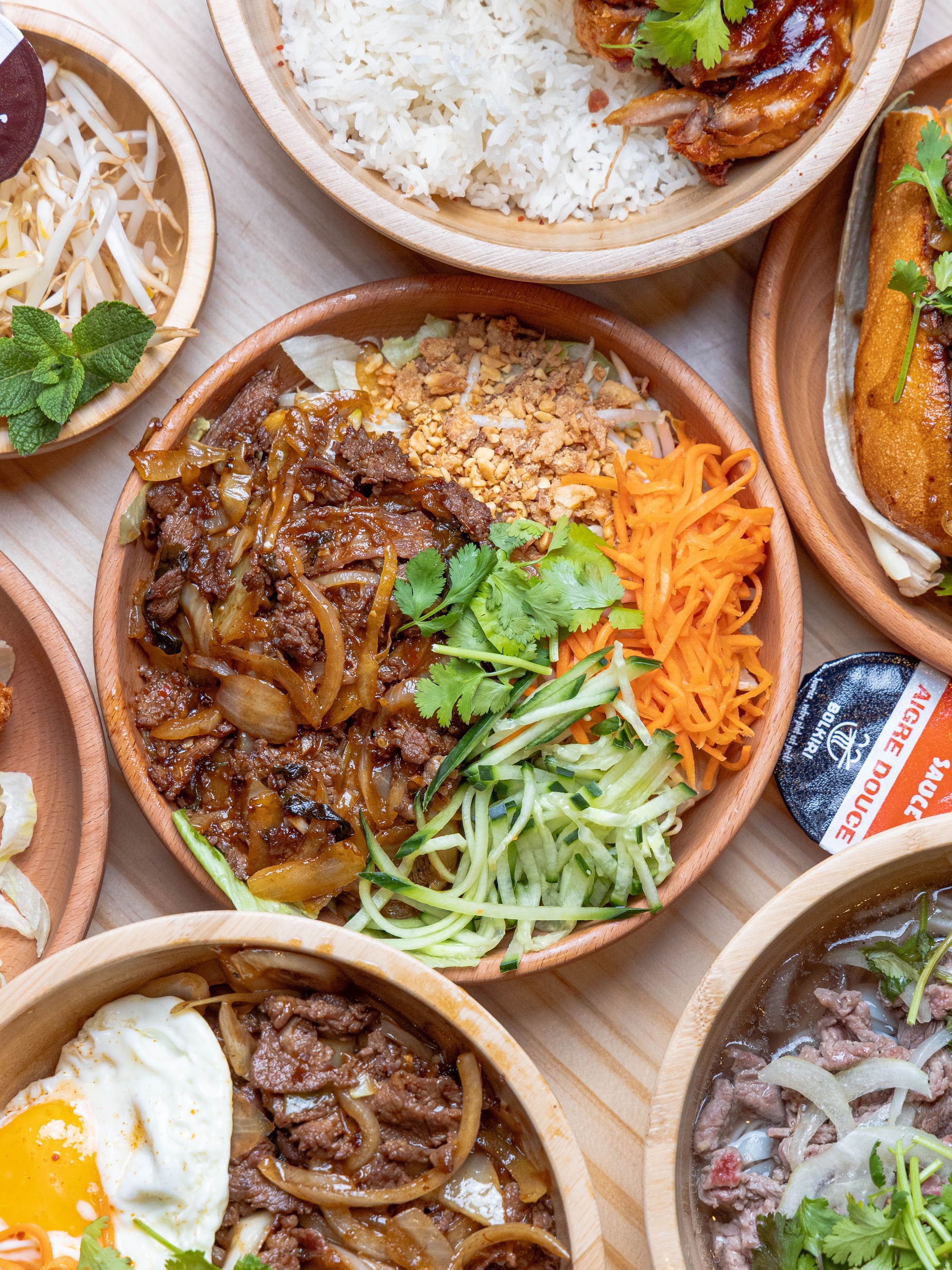 Plat asiatique avec bœuf sauté, carottes râpées, concombre, cacahuètes et coriandre au restaurant asiatique.