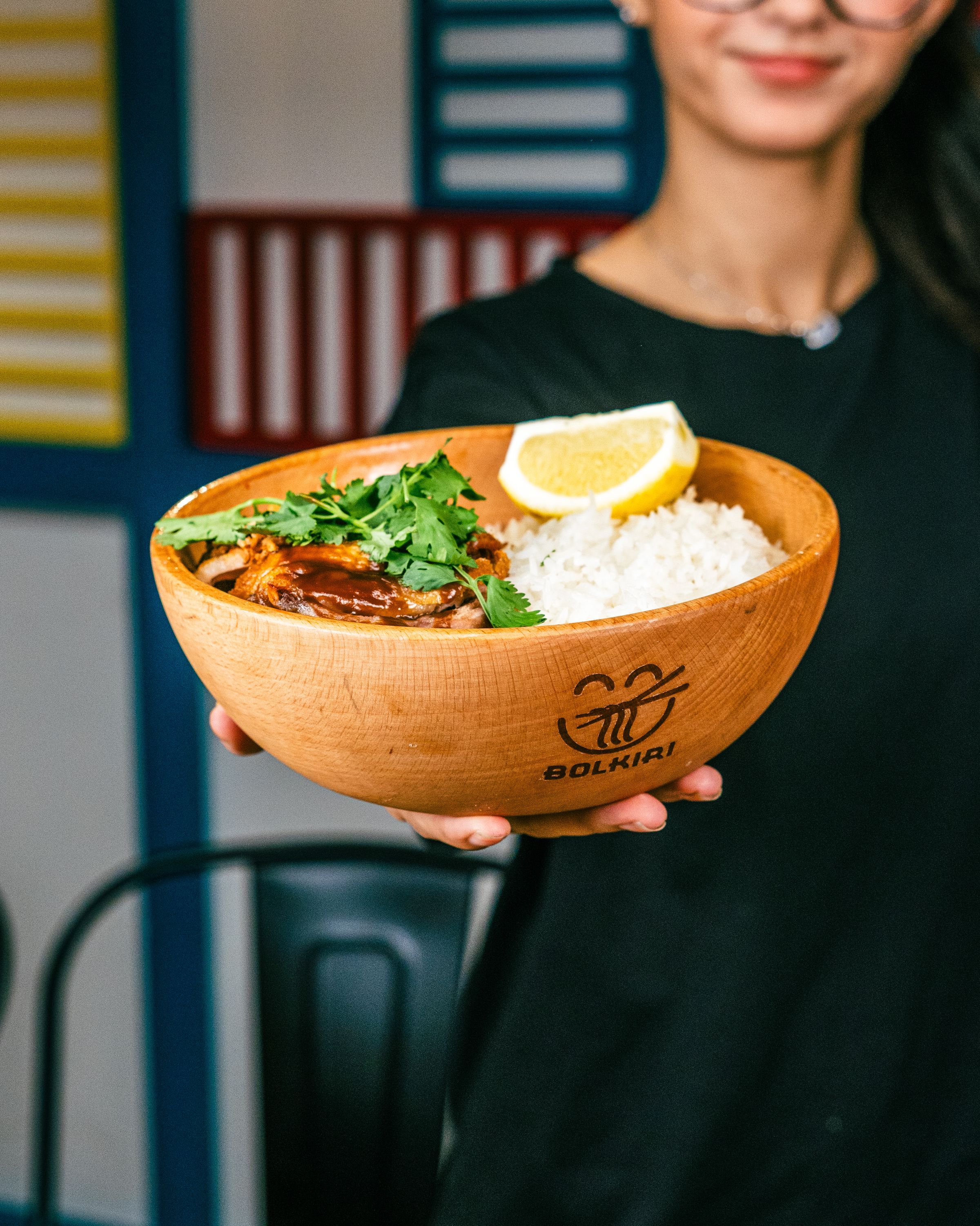 Bol tranche de poulet caramélisé avec riz et herbes fraîches dans un bol en bois au restaurant BOLKIRI.