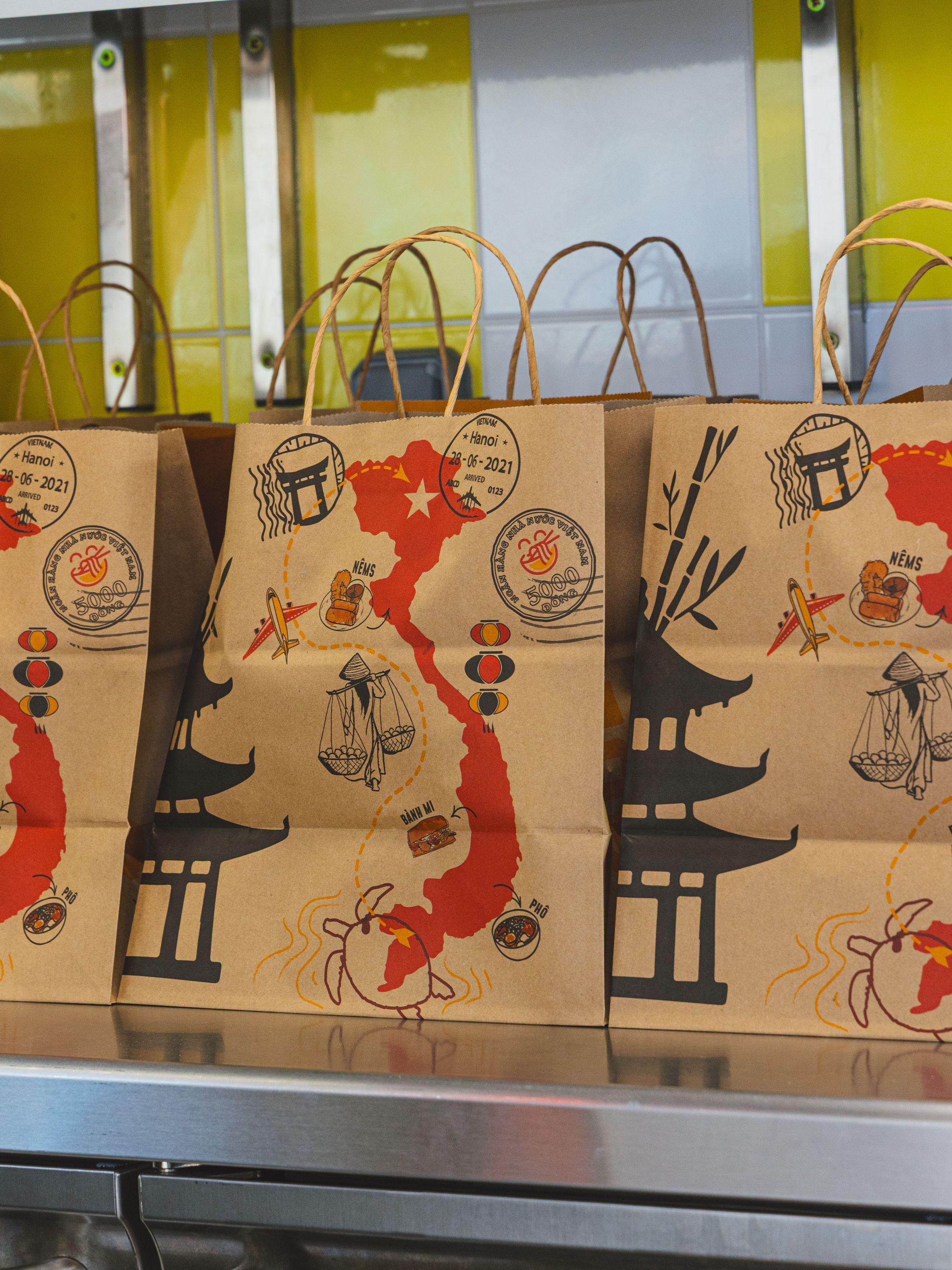 Sacs en papier décorés d'illustrations vietnamiens alignés sur un comptoir dans un restaurant asiatique.