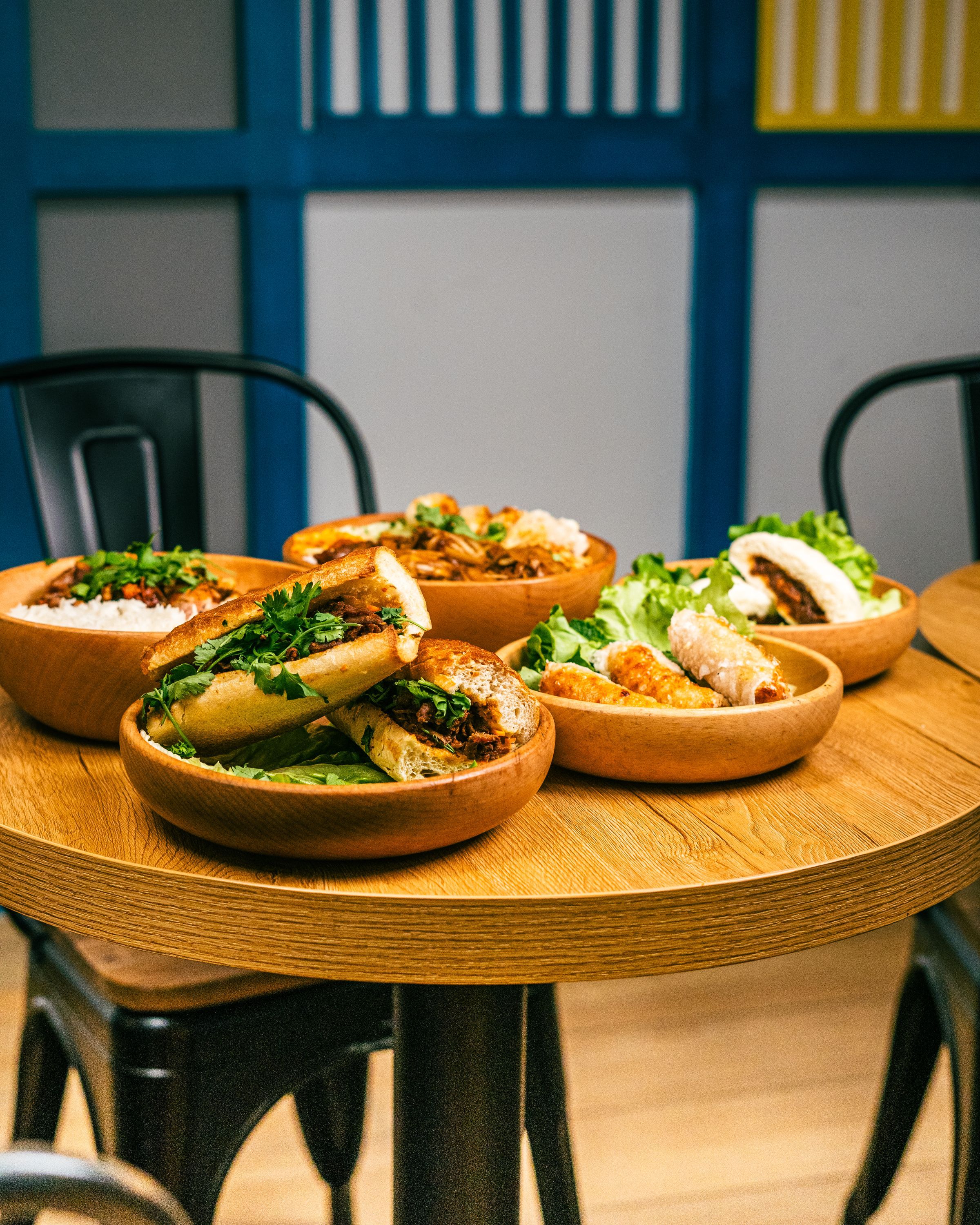 Plats de street food vietnamiens, incluant sandwiches et salades, présentés dans des bols en bois.