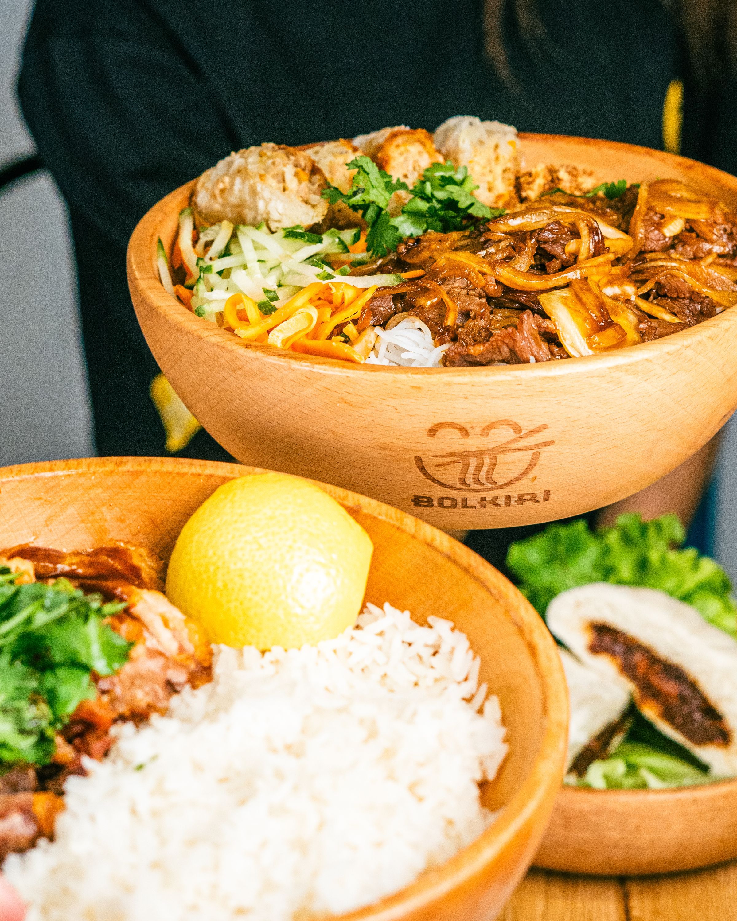 Bol Vietnamese street food avec boisson, herbes fraîches et légumes colorés dans des bols en bois.