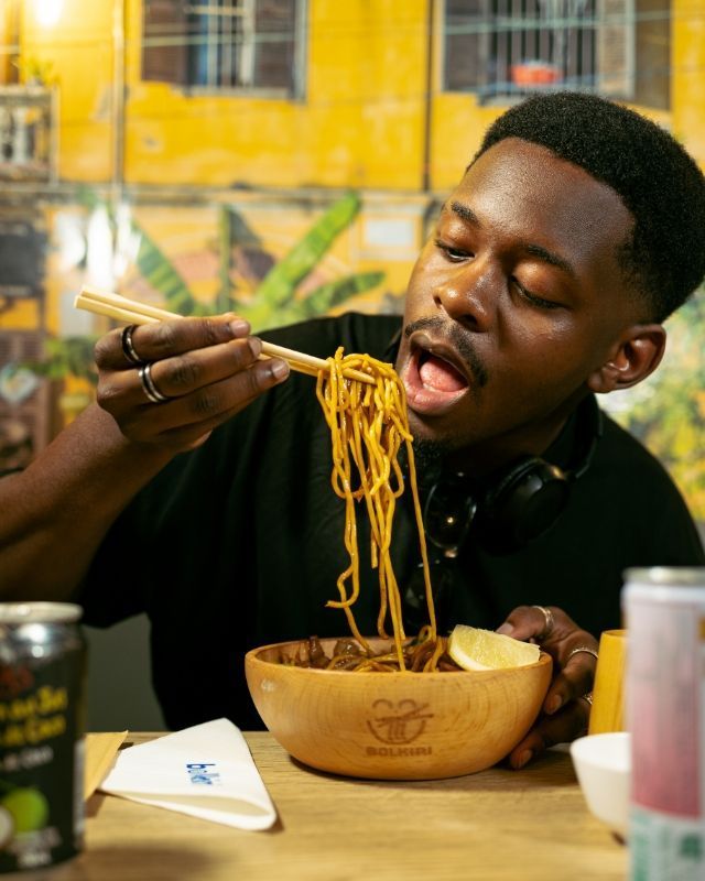 Un homme déguste des nouilles dans un restaurant asiatique, utilisant des baguettes.