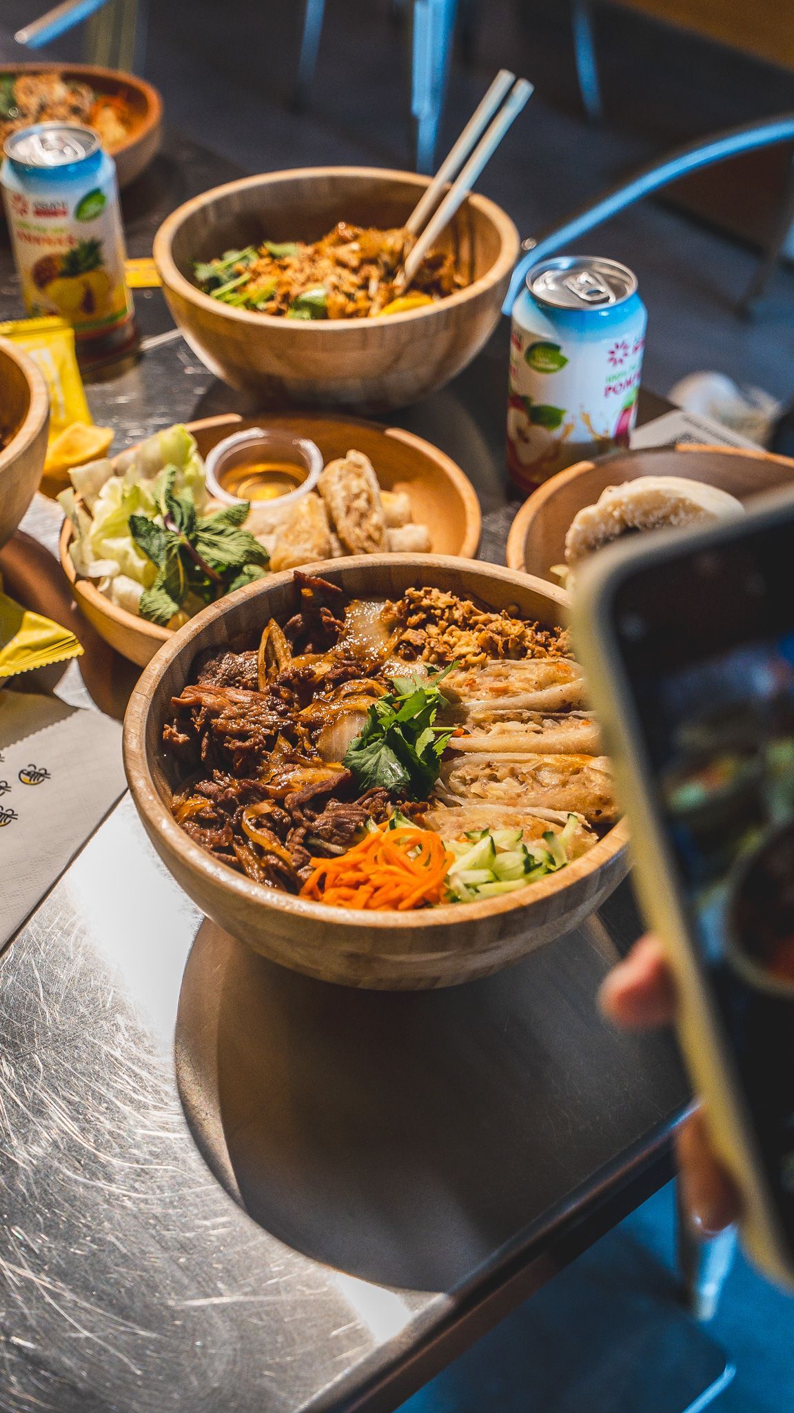Bols de street food vietnamien avec viandes, légumes frais et accompagnements dans un restaurant asiatique.