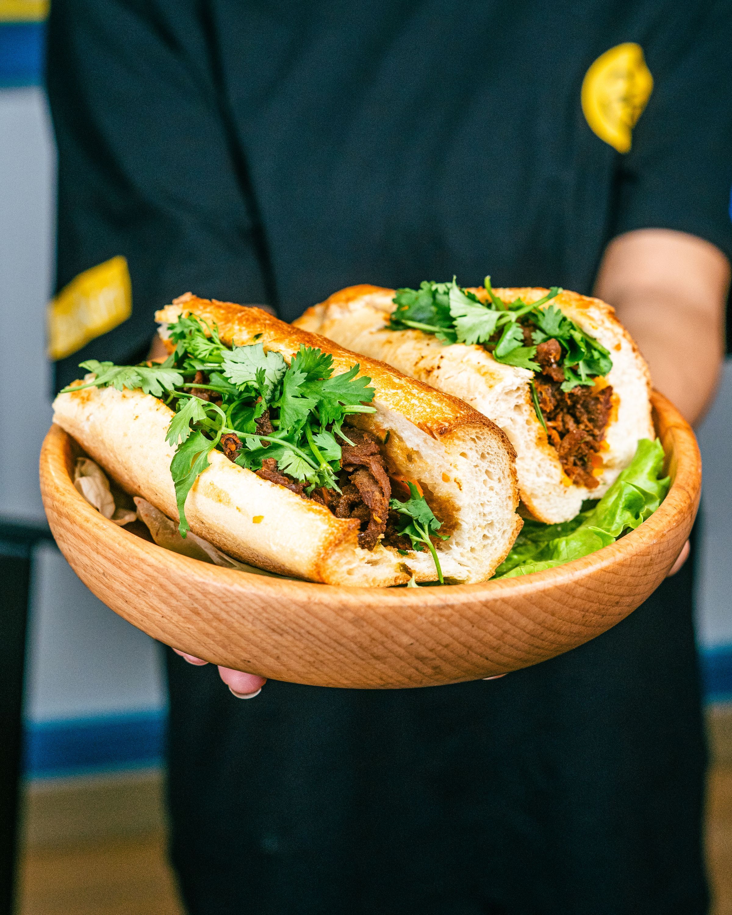 Sandwichs vietnamiens garnis de viande et de coriandre, servis dans un bol en bois.