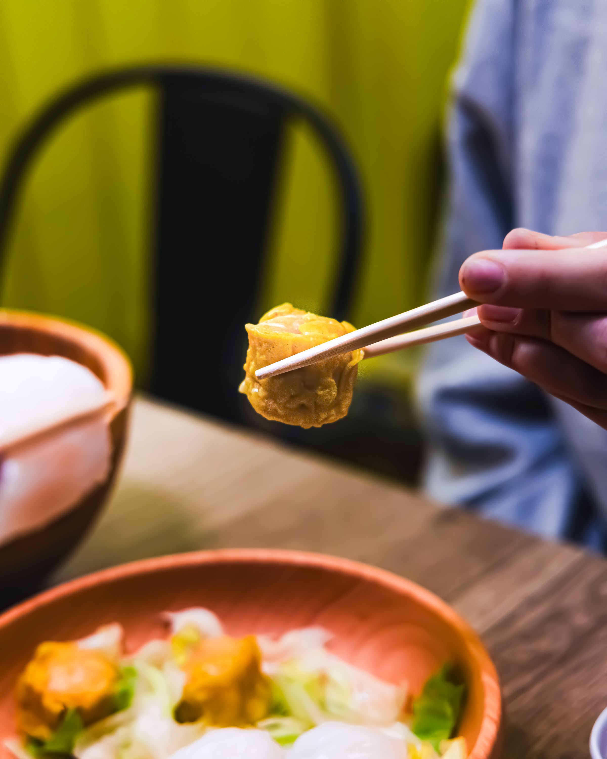 Un client déguste des mets asiatiques avec des baguettes dans un restaurant de street food.