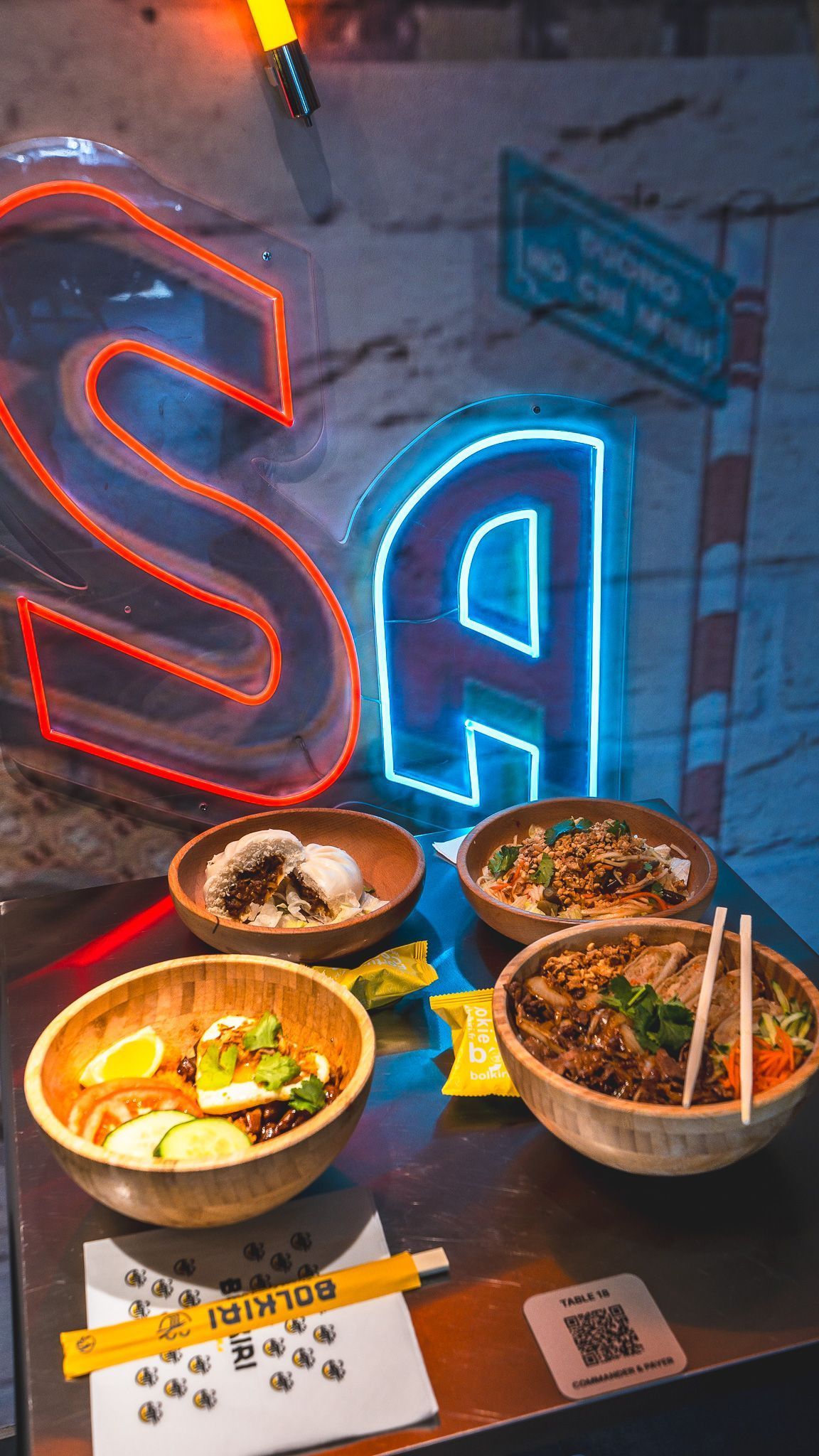 Quatre bols de plats asiatiques variés sur une table en métal dans un restaurant asiatique.