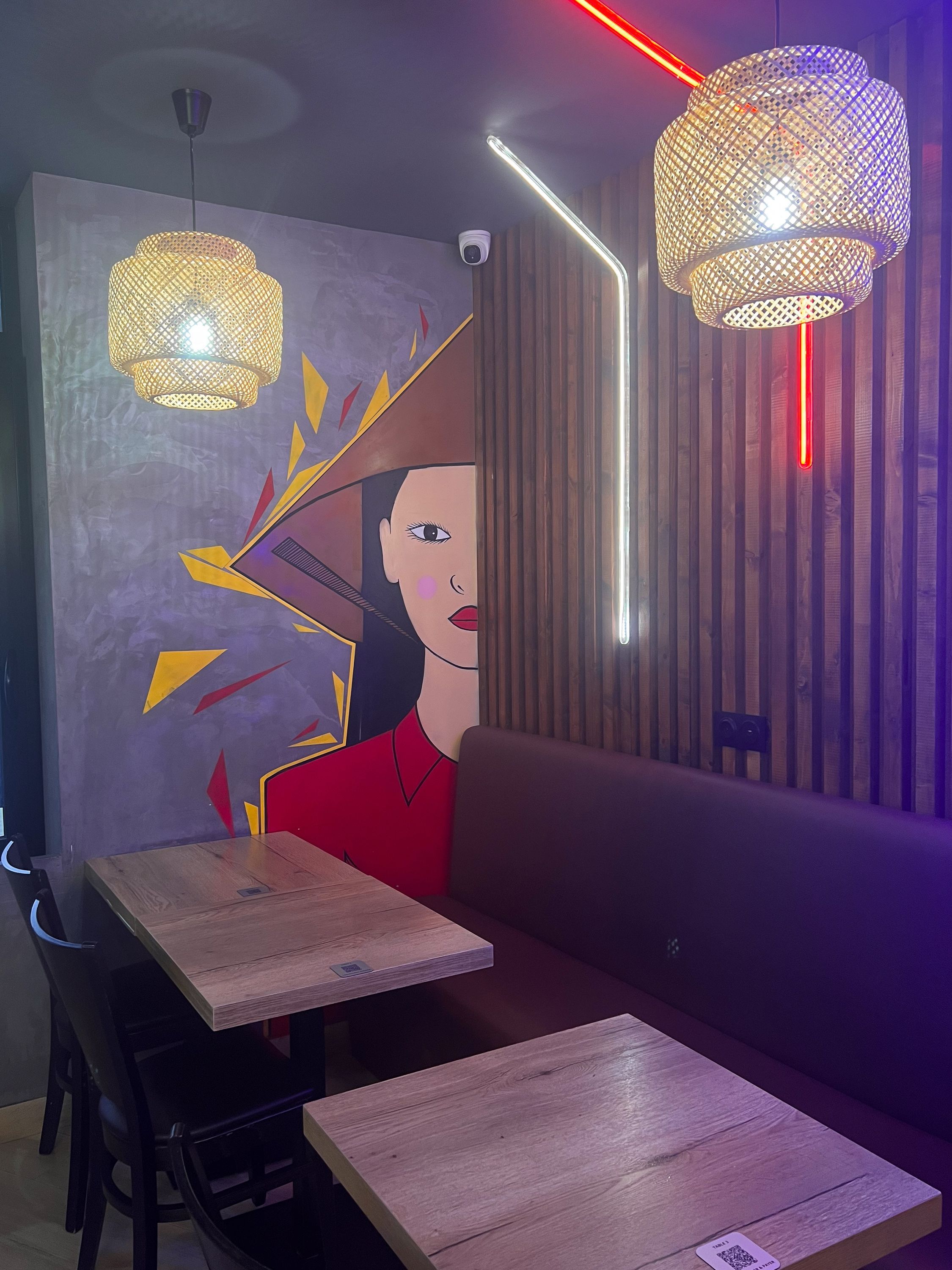 Ambiance moderne avec des tables en bois dans un restaurant asiatique, décoré d'une fresque vietnamienne.