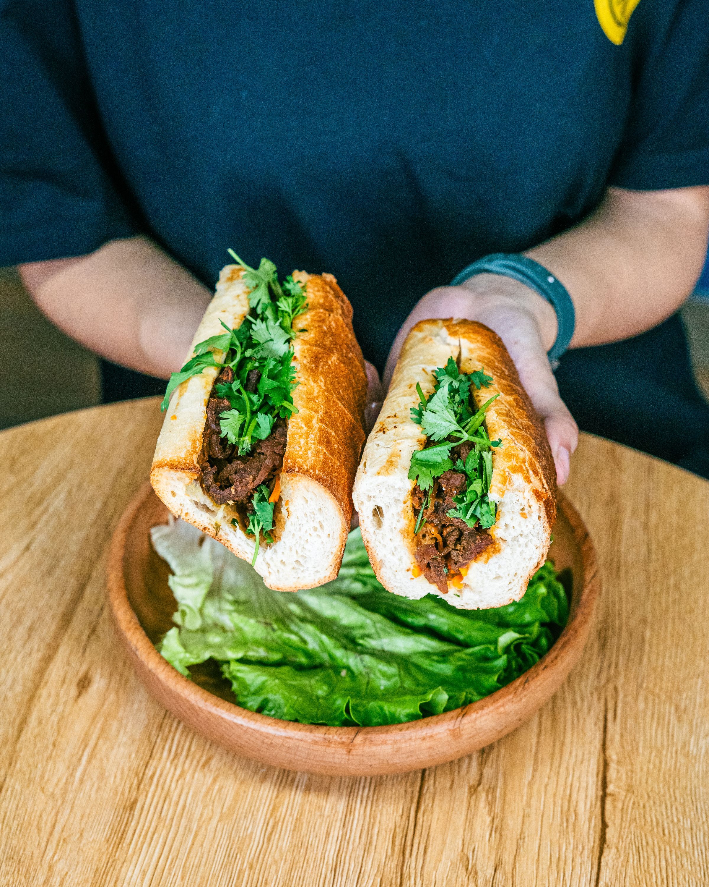 Sandwichs vietnamiens garnis de viande et de coriandre, accompagnés de salade au restaurant asiatique.